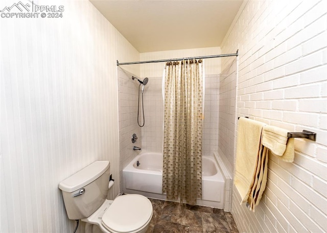 bathroom featuring tile floors, brick wall, toilet, and shower / bath combo with shower curtain