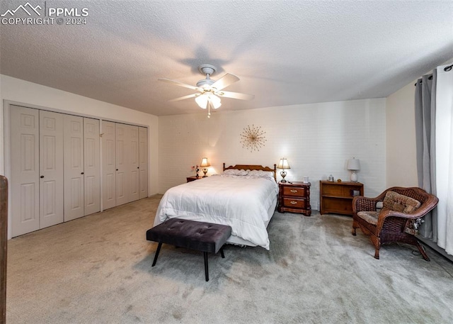 bedroom featuring a closet, light carpet, ceiling fan, and a textured ceiling