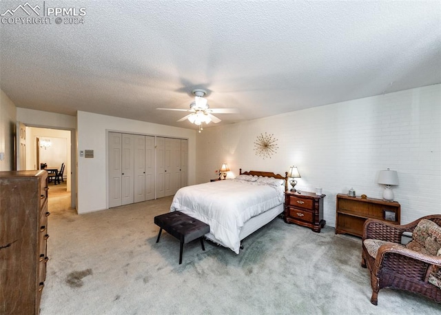 bedroom with light colored carpet, a closet, ceiling fan, and a textured ceiling