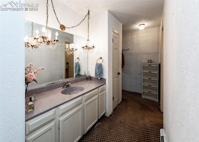 bathroom with a textured ceiling, vanity, and a notable chandelier