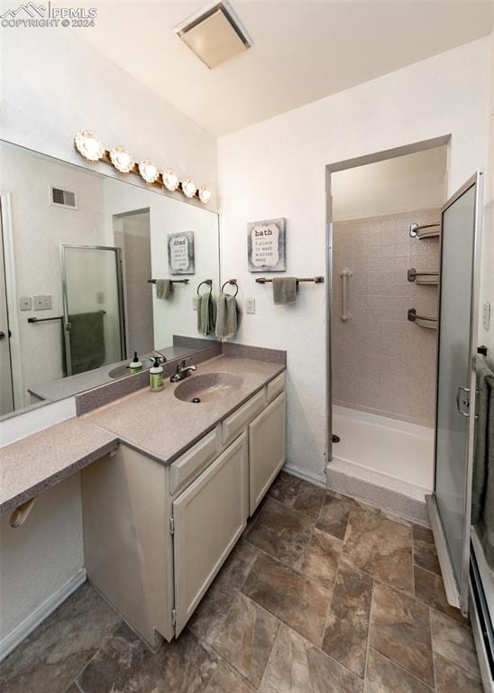 bathroom with tile flooring, vanity with extensive cabinet space, and a shower with shower door