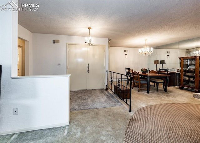 foyer with light carpet, a textured ceiling, and an inviting chandelier