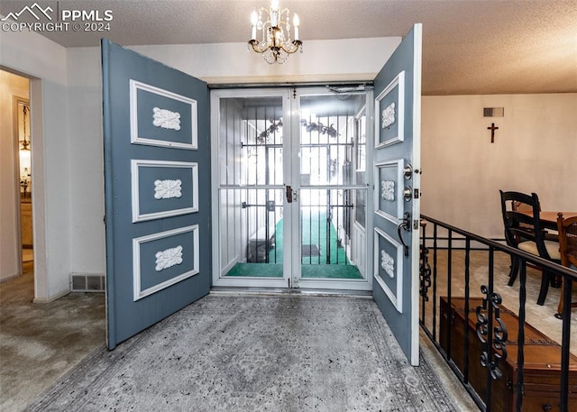 entryway with a textured ceiling, french doors, and an inviting chandelier