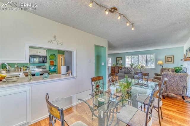 dining area featuring a textured ceiling, light hardwood / wood-style floors, and sink