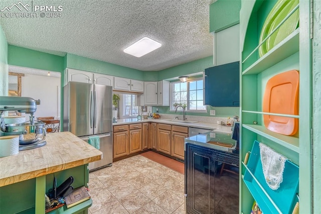 kitchen with a textured ceiling, sink, white cabinets, butcher block countertops, and stainless steel refrigerator