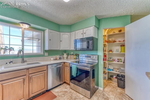 kitchen featuring sink, white cabinetry, stainless steel appliances, and light tile patterned floors