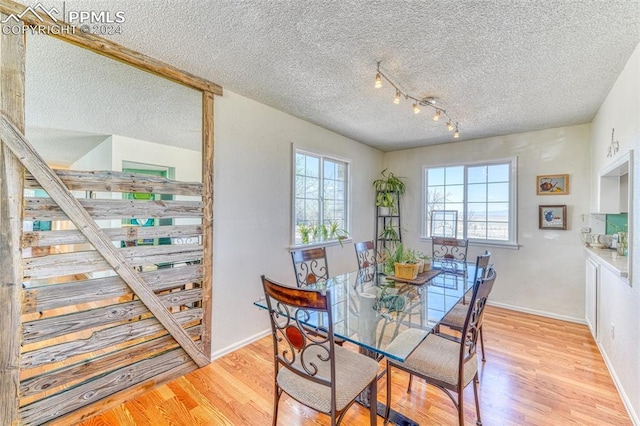 dining area with light hardwood / wood-style floors and a textured ceiling