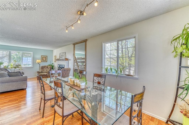 dining space with a healthy amount of sunlight, a textured ceiling, and light hardwood / wood-style floors