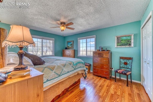 bedroom with ceiling fan, light hardwood / wood-style floors, multiple windows, and a closet