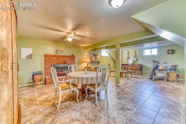 dining area featuring a textured ceiling, ceiling fan, and a fireplace