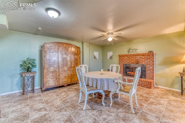 dining space featuring a fireplace, a textured ceiling, and ceiling fan