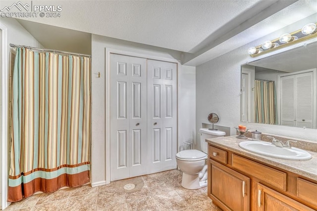 bathroom with a textured ceiling, vanity, and toilet