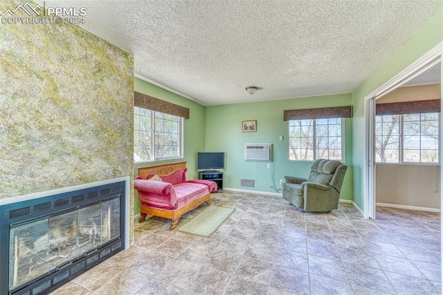 living area featuring a large fireplace, a textured ceiling, and a wall unit AC