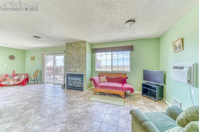 living room featuring an AC wall unit, a fireplace, and a textured ceiling