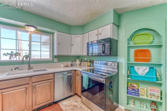 kitchen with light tile patterned floors, a textured ceiling, stainless steel appliances, and sink