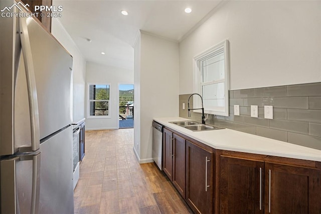 kitchen featuring backsplash, stainless steel appliances, sink, light hardwood / wood-style floors, and dark brown cabinetry