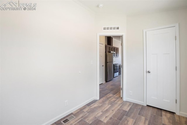 empty room with ornamental molding and hardwood / wood-style flooring