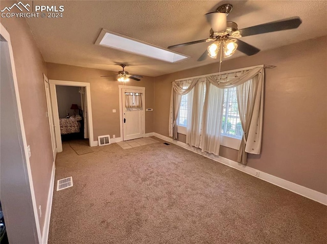 spare room with a textured ceiling, ceiling fan, and carpet