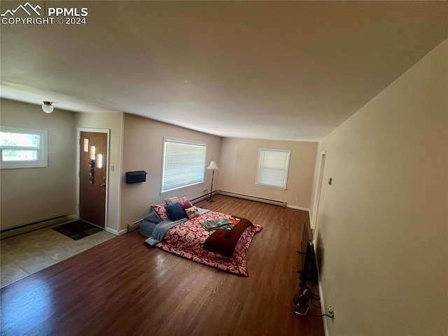 unfurnished living room featuring hardwood / wood-style flooring, a healthy amount of sunlight, and baseboard heating