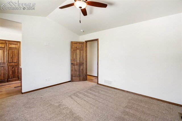 carpeted spare room featuring ceiling fan and vaulted ceiling