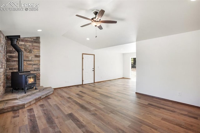 unfurnished living room with ceiling fan, a wood stove, wood-type flooring, and lofted ceiling