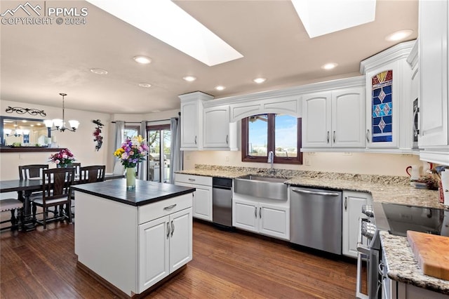 kitchen with a skylight, white cabinets, stainless steel dishwasher, hanging light fixtures, and stove