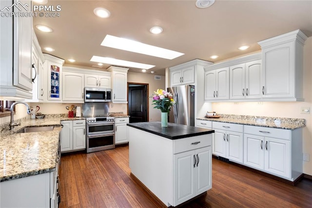 kitchen with a center island, dark hardwood / wood-style flooring, white cabinetry, appliances with stainless steel finishes, and a skylight