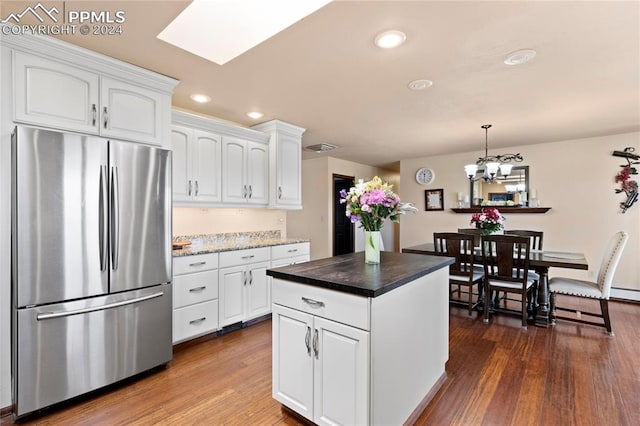 kitchen with a center island, stainless steel refrigerator, white cabinetry, dark hardwood / wood-style flooring, and hanging light fixtures