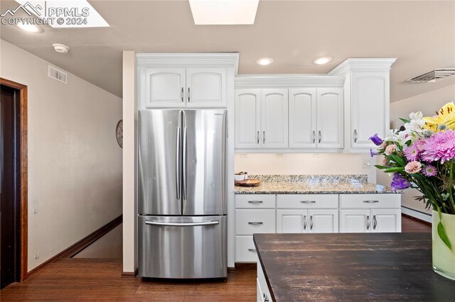 kitchen featuring light stone countertops, dark hardwood / wood-style floors, stainless steel fridge, white cabinets, and a baseboard radiator