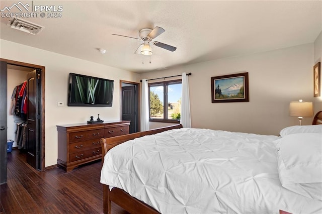 bedroom with a closet, dark wood-type flooring, ceiling fan, and a walk in closet