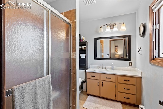 bathroom featuring vanity with extensive cabinet space, toilet, tile flooring, and walk in shower