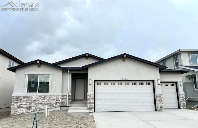 view of front of property featuring a garage, stone siding, concrete driveway, and stucco siding