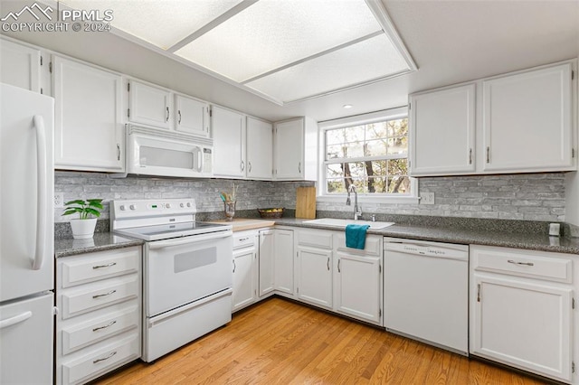 kitchen with light hardwood / wood-style flooring, white appliances, sink, and white cabinetry