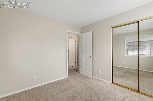 unfurnished bedroom featuring light colored carpet and a closet