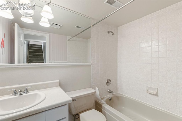 full bathroom featuring vanity with extensive cabinet space, tiled shower / bath, and toilet