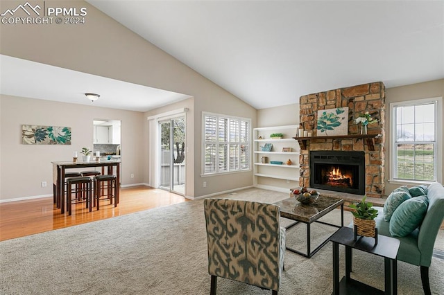 living room with high vaulted ceiling, light wood-type flooring, built in features, and a stone fireplace