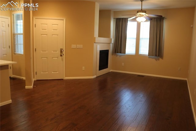 unfurnished living room featuring ceiling fan and dark hardwood / wood-style flooring