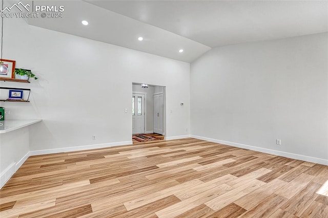 empty room featuring vaulted ceiling and light hardwood / wood-style floors