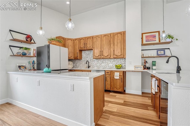 kitchen with light hardwood / wood-style flooring, stainless steel refrigerator, sink, and decorative backsplash