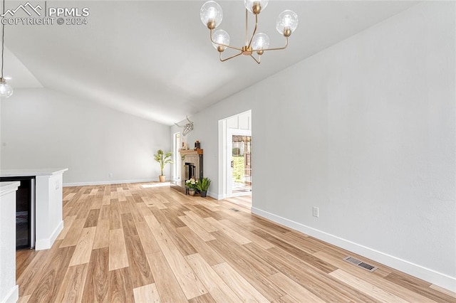 unfurnished living room featuring vaulted ceiling, light hardwood / wood-style flooring, and a chandelier