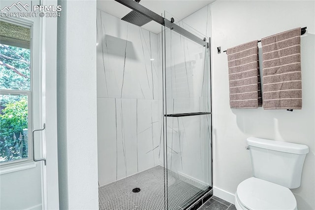 bathroom featuring toilet, a shower with door, and tile patterned floors