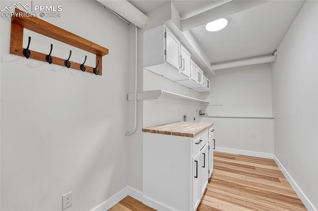 kitchen featuring light wood-type flooring, wooden counters, and white cabinetry