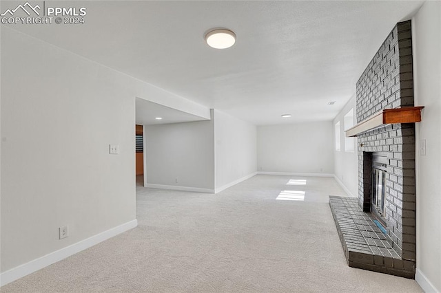 unfurnished living room featuring light colored carpet and a brick fireplace