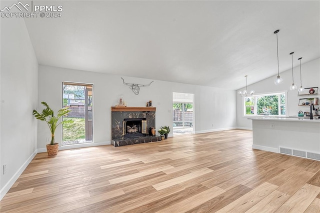 living room featuring a wealth of natural light, light hardwood / wood-style flooring, vaulted ceiling, and a high end fireplace