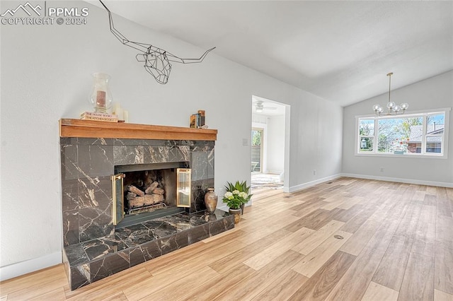 unfurnished living room featuring vaulted ceiling, a tiled fireplace, ceiling fan with notable chandelier, and wood-type flooring