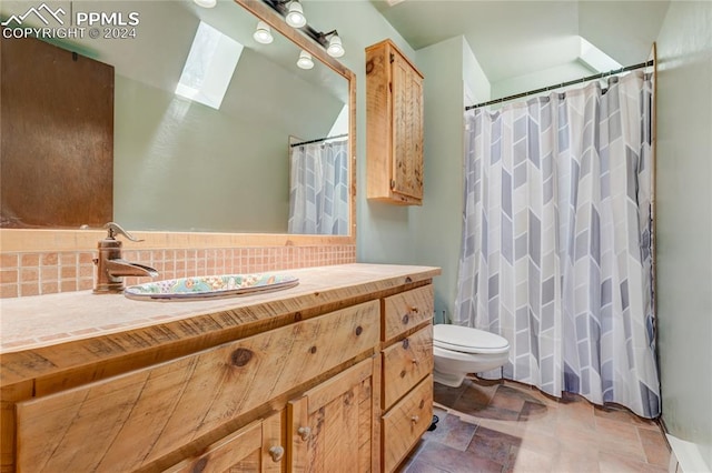 bathroom with tile flooring, vanity, toilet, and a skylight