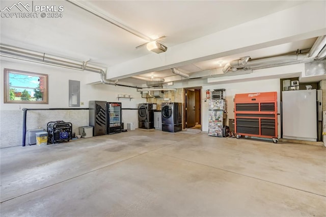 garage featuring white refrigerator, washer and clothes dryer, and a garage door opener