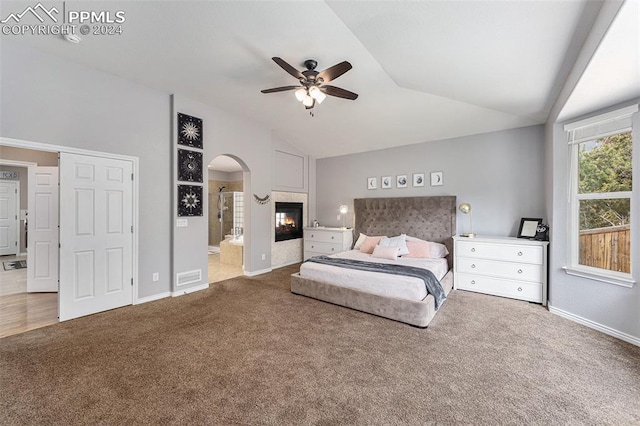 bedroom with ceiling fan, light carpet, vaulted ceiling, and ensuite bathroom