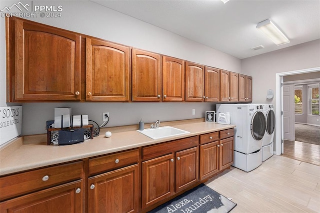 laundry area with sink, washing machine and dryer, light colored carpet, and cabinets