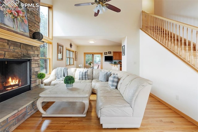 living room featuring ceiling fan, light wood-type flooring, a healthy amount of sunlight, and a fireplace